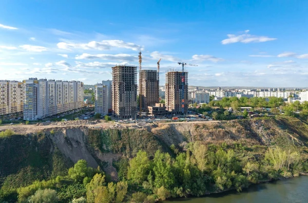 Строящиеся высотные дома над зелёным склоном